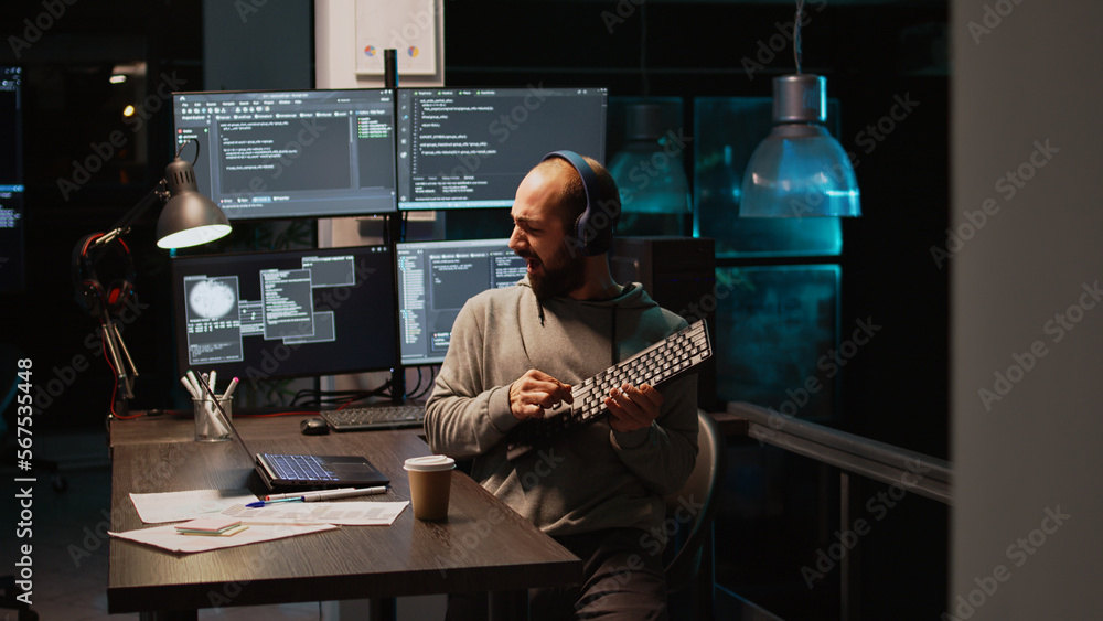 Aufkleber app developer playing air guitar in coding office, enjoying music and song late at night. having fun