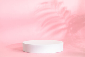 Pink background for product presentation with shadow of tropical palm leaves and light. Podium, stage pedestal platform for cosmetic product. Empty round podium. Mockup.