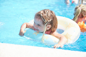 child girl 3 years old swims in the pool in the summer outdoors