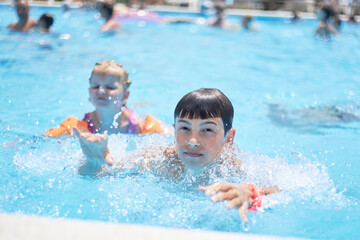 Fototapeta na wymiar boy swimming in the pool in summer outdoor kids pool