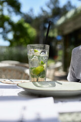 Summer mint refreshing mojito cocktail with ice in a glass outdoors in a cafe.