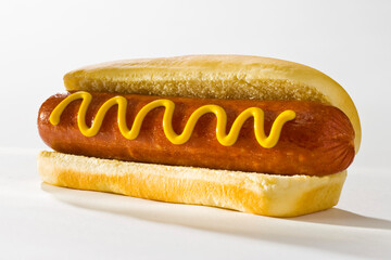 Hotdog with wavy stripe of mustard on a bun on a white background