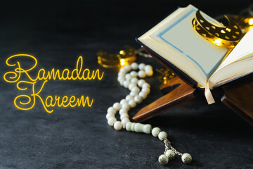 Greeting card for Ramadan with Koran and prayer beads on dark background