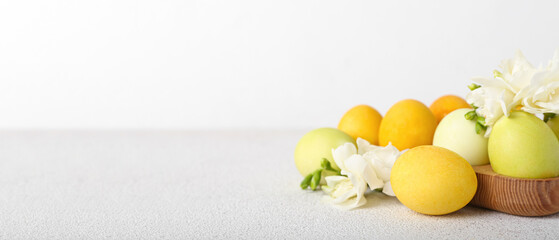 Painted Easter eggs and flowers on light background with space for text