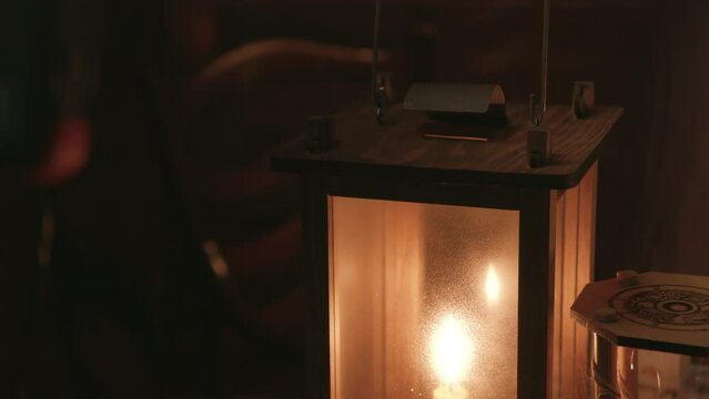 18th century man placing a candle lantern on a desk
