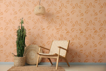 Green cactus with wicker armchair near beige wall in room