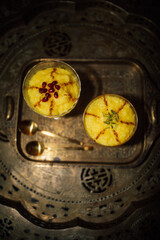 Sholeh Zard: bright yellow Persian dessert made from rice, saffron with pomegranate and cinnamon garnish