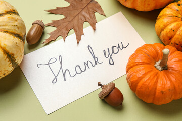Paper sheet with text THANK YOU, pumpkins, acorns and leaf on green background