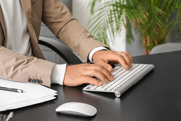 Young businessman working with computer at table in office, closeup