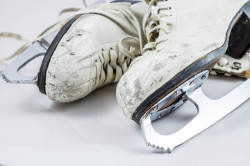 White figure skates scuffed from years of use on a white background.