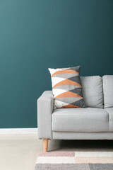 Grey sofa with cushion near green wall