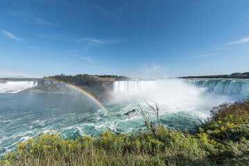 A tour boat at the end of a rainbow takes tourists to the base of the Horseshoe Falls in Niagara...