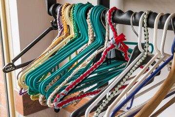 A close up of various colored hangers hanging on a coat rack.