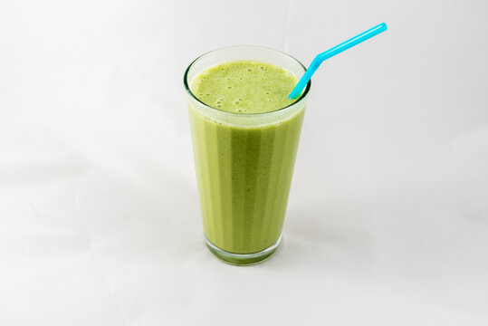 A bent blue straw sits in a green smoothie.