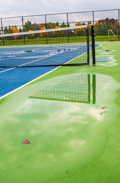 A tennis net reflects in a puddle after a rain storm.