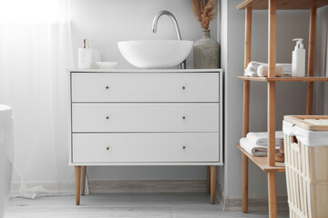 Fototapeta na wymiar Chest of drawers with sink and vase in light bathroom