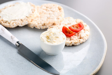 Plate with tasty crispbreads and cream cheese on grey background, closeup