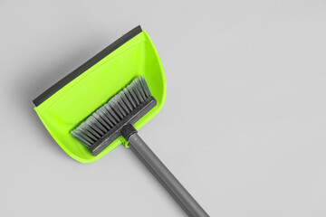 Cleaning broom with green dustpan on white background