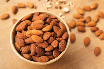 Bowl of almond nuts on wooden background, closeup