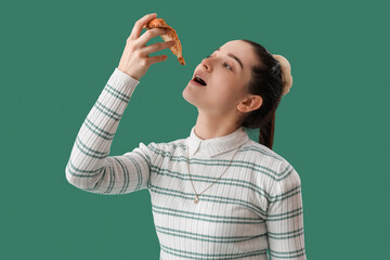 Young woman with slice of tasty pizza on green background