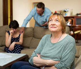 Senior woman sitting during family conflict, woman crying while quarrel with man