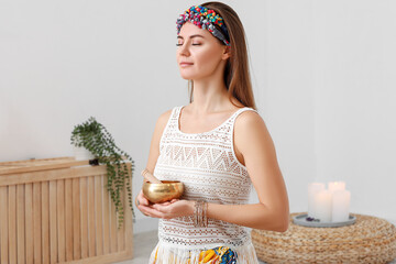 Young woman with Tibetan singing bowl at home