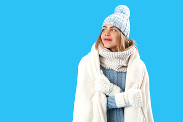 Frozen young woman in warm plaid on blue background