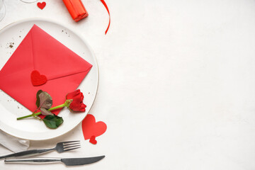 Table setting for Valentine's Day with envelope and rose on white table