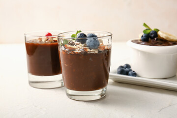 Glasses and bowl with delicious chocolate pudding, berries, nuts and banana on white table