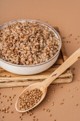 Board with bowl of tasty buckwheat porridge on beige background