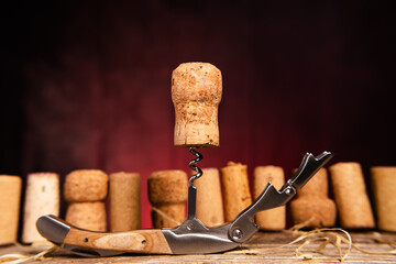 Wine cork on a corkscrew close-up against the background of used corks on a wooden table. Red...