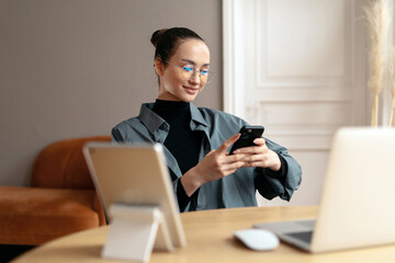 Sitting in the office during the day working business woman freelancer in a shirt, office employee assistant using the phone in her hands.