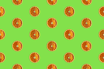 Colorful fruit pattern of fresh orange slices on vivid green background. From top view