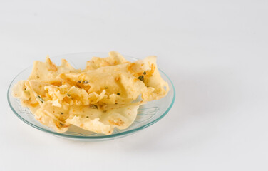 rempeyek teri or anchovies, a typical Indonesian food made from flour mixed with small fish and then deep fried, served on a small plate isolated on a white background
