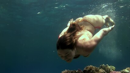 Cameraman shoots video young woman underwater model mermaid. Creativity and art of creating images on background of seabed.