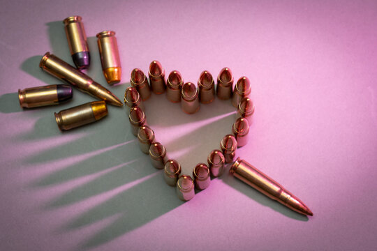 Tactical equipment and Valentine's day.  Ar 15 rifle, silencer, M1911 pistol, heart made of bullets, heart shaped balloon, night vision device and American flag patch.