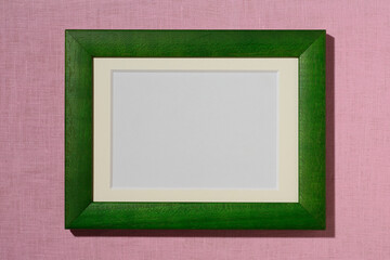 ピンクの壁に掛かった緑の額縁