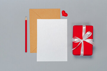 Flat lay composition of craft paper envelope and blank white card isolated on grey background