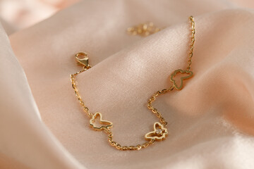Gold  bracelet with butterflies and diamond on pink background. Romantic jewelry. Advertising still...