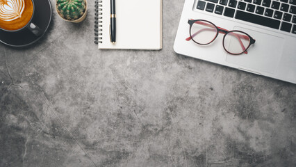 Dark office desk workplace with laptop, eyeglass, pen, notebook and cup of coffee, Top view flat lay with copt space.