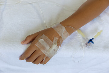 Photo of a hand with an IV in a hospital.Asian woman lying sick in hospital