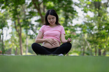 Asian healthy pregnant woman doing yoga exercise in the park