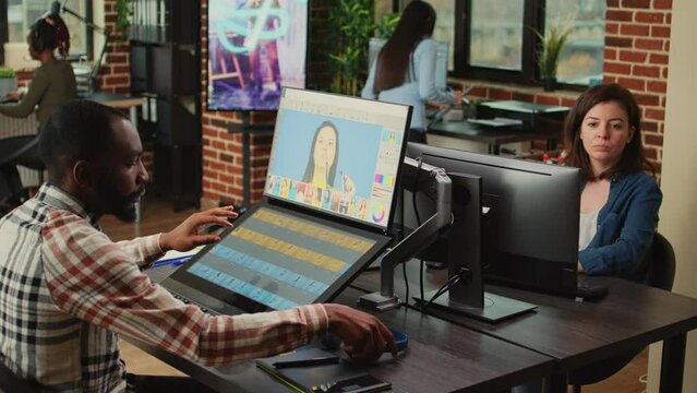 Young content creator retouching photos with color grading, using touchscreen monitor and stylus. Image editor with graphic tablet using editing software to retouch picture in agency studio.