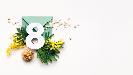 Number 8 on paper envelope with fresh mimosa flowers, symbol of Spring. International Women's day greeting flat lay on off white paper, panoramic banner design.