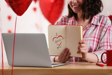 Valentine's day celebration in long distance relationship. Woman having video chat with her boyfriend via laptop indoors, closeup
