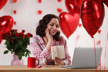Fototapeta na wymiar Valentine's day celebration in long distance relationship. Woman having video chat with her boyfriend via laptop indoors