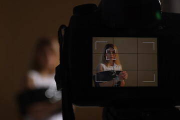 Woman taped up and taken hostage on dark background, view through camera screen