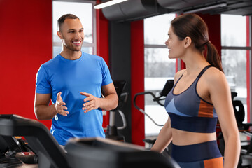 Fototapeta premium Happy trainer explaining woman how to do exercise properly in modern gym