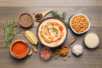 Delicious hummus with chickpeas and different ingredients on wooden table, flat lay