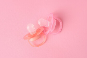 New baby pacifiers on pink background, flat lay